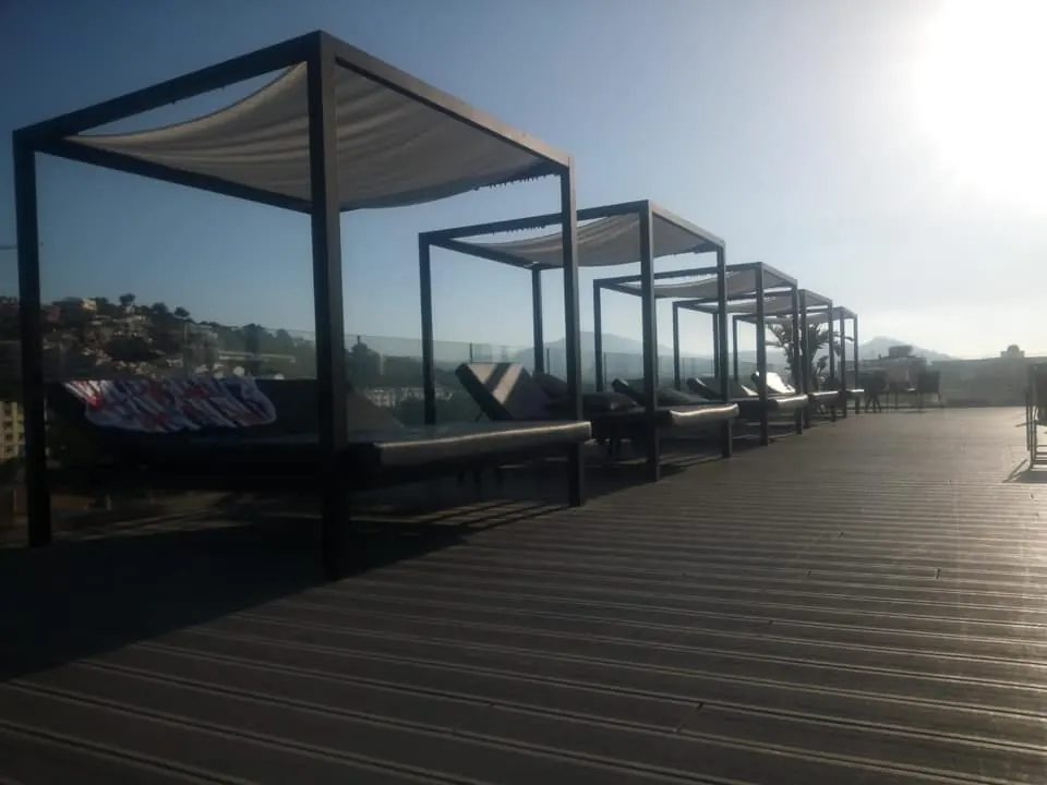 Camas balinesas con techo textil en la terraza de un hotel al atardecer