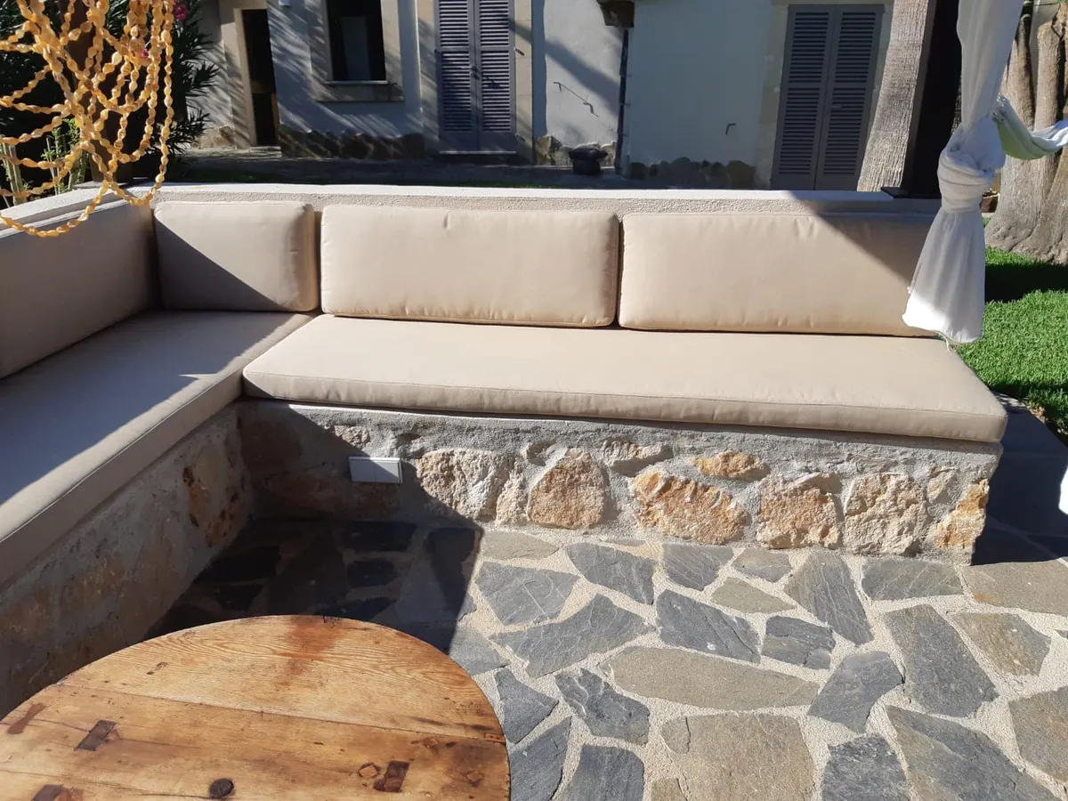 Cojines de exterior a medida sobre banco de obra en un patio mallorquín