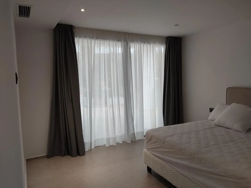 Conjunto de visillo blanco y cortina gris en dormitorio principal
