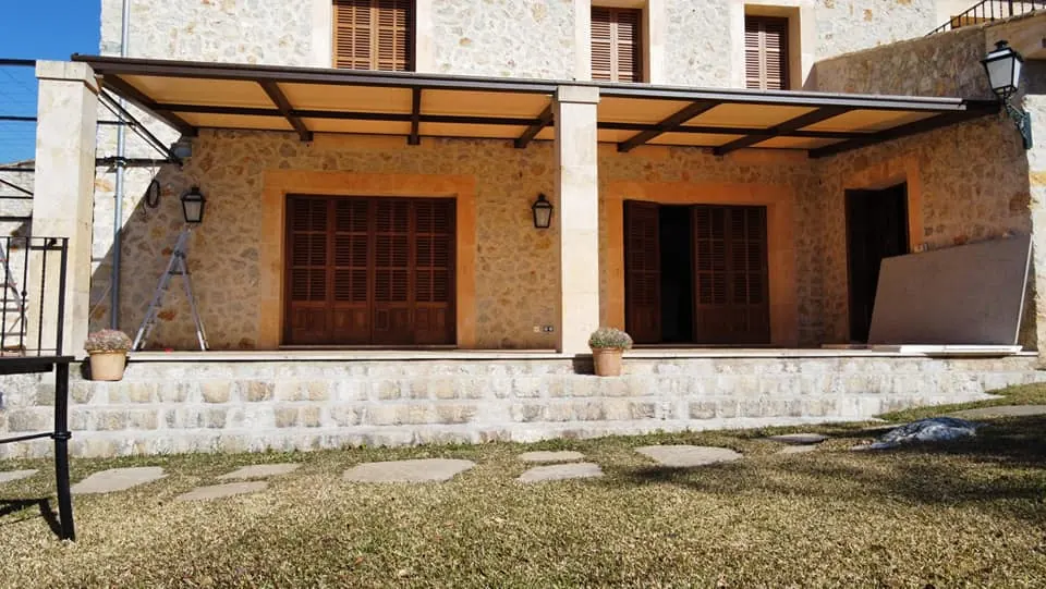 Estructura de pérgola metálica instalada en casa de piedra mallorquina