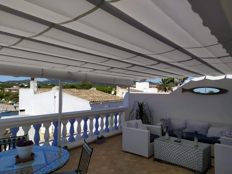 Pérgola con toldo corredero blanco en una terraza junto al puerto