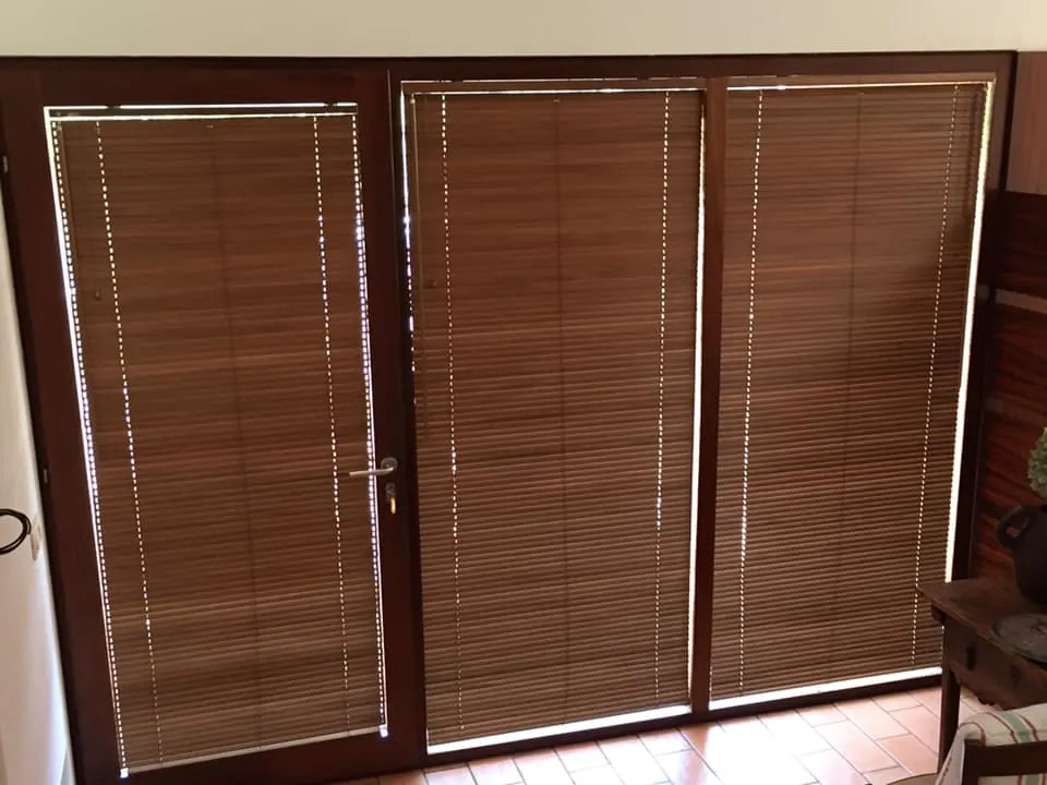 Persianas venecianas de madera instaladas en puertas acristaladas