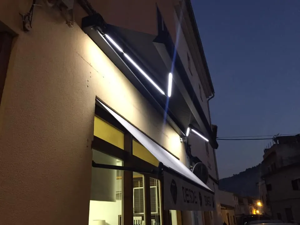 Toldo cofre con iluminación LED integrada en fachada, vista nocturna