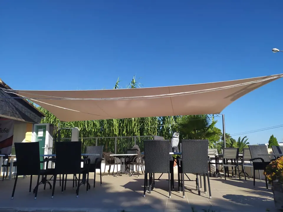 Vela tensada rectangular sobre la terraza de un bar